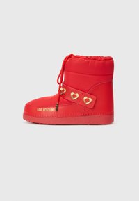 Red ankle boots with a padded design, featuring a gold heart-accented strap and a logo detail. Textured rubber sole for grip.