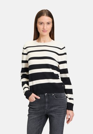 Pull à rayures noir et blanc avec col rond, manches longues et ourlet côtelé. Texture en tricot douce. Associé à un jean sombre.