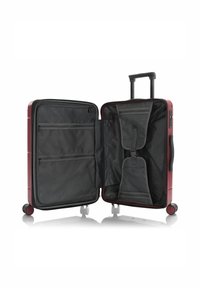 Roter Hartschalenkoffer, geöffnet, um das schwarze Innenfutter mit Netz-Reißverschlusstaschen, verstellbaren Gurten und einem Teleskopgriff für den Transport zu zeigen.