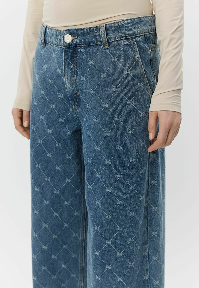 Blå denimjeans med diamantmønster, udstyret med knaplukning og design med fem lommer. Vidtnået ben med en struktureret overflade.