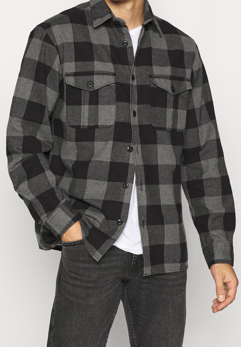 Grå och svart rutig flanellskjorta med två bröstfickor, knappframsida och långa ärmar. Mjuk textur, avslappnad passform och klassiskt mönster.