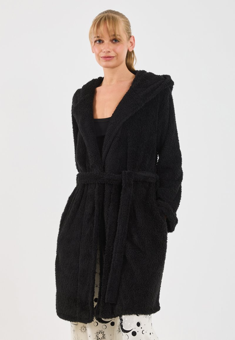 Rochie de baie neagră, pufoasă, cu glugă, talie închisă cu un cordon și două buzunare frontale. Textură moale și design de lungime medie.