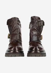 Bottes en cuir brun au design légèrement décontracté, dotées de larges sangles, de boucles sur les côtés et de semelles en caoutchouc texturé.