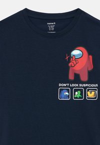 Granatowy bawełniany t-shirt z czerwoną postacią z kreskówki trzymającą palec przy ustach oraz napisem "NIE WYGLĄDAJ PODEJRZEANIE", pod którym znajdują się cztery małe ikony.