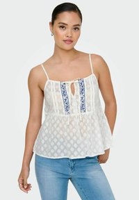 Top peplum blanco con tirantes ajustables tipo espagueti, que presenta un escote en forma de llave y bordado floral azul en la parte delantera. Tejido texturizado con un patrón de diamante.