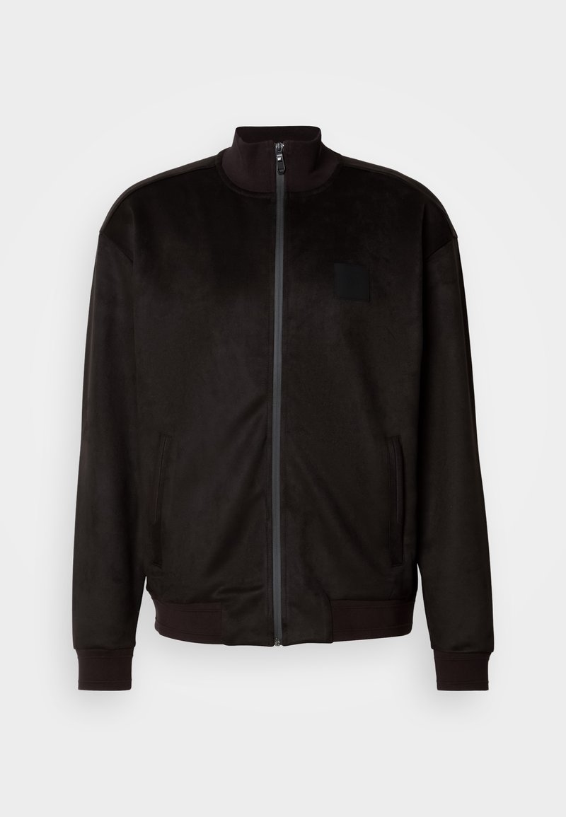 Schwarze Zip-Jacke mit Stehkragen, aus weichem Stoff gefertigt. Verfügt über seitliche Taschen und ein kleines rechteckiges Patch auf der Brust.