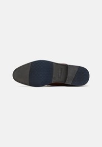 Schoenenzool met bovenwerk van bruin leer, rubberiseerbare grijze sectie, getextureerde navy rubberen onderkant en geperst merkteken.