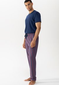 Top corto blu della marina a maniche corte abbinato a pantaloni da pigiama a righe rosse e blu con vita elastica e coulisse. Il tessuto sembra morbido.