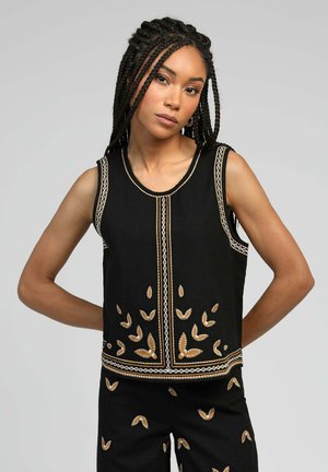 Haut sans manches noir avec des motifs de feuilles brodés en or et blanc, présentant un col rond et une coupe droite. Tissu texturé.