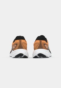 Oranje en zwarte sportschoenen met een gestructureerd mesh bovenwerk, een gewatteerde witte zool en een zwarte rubberen loopzool met grippatronen.