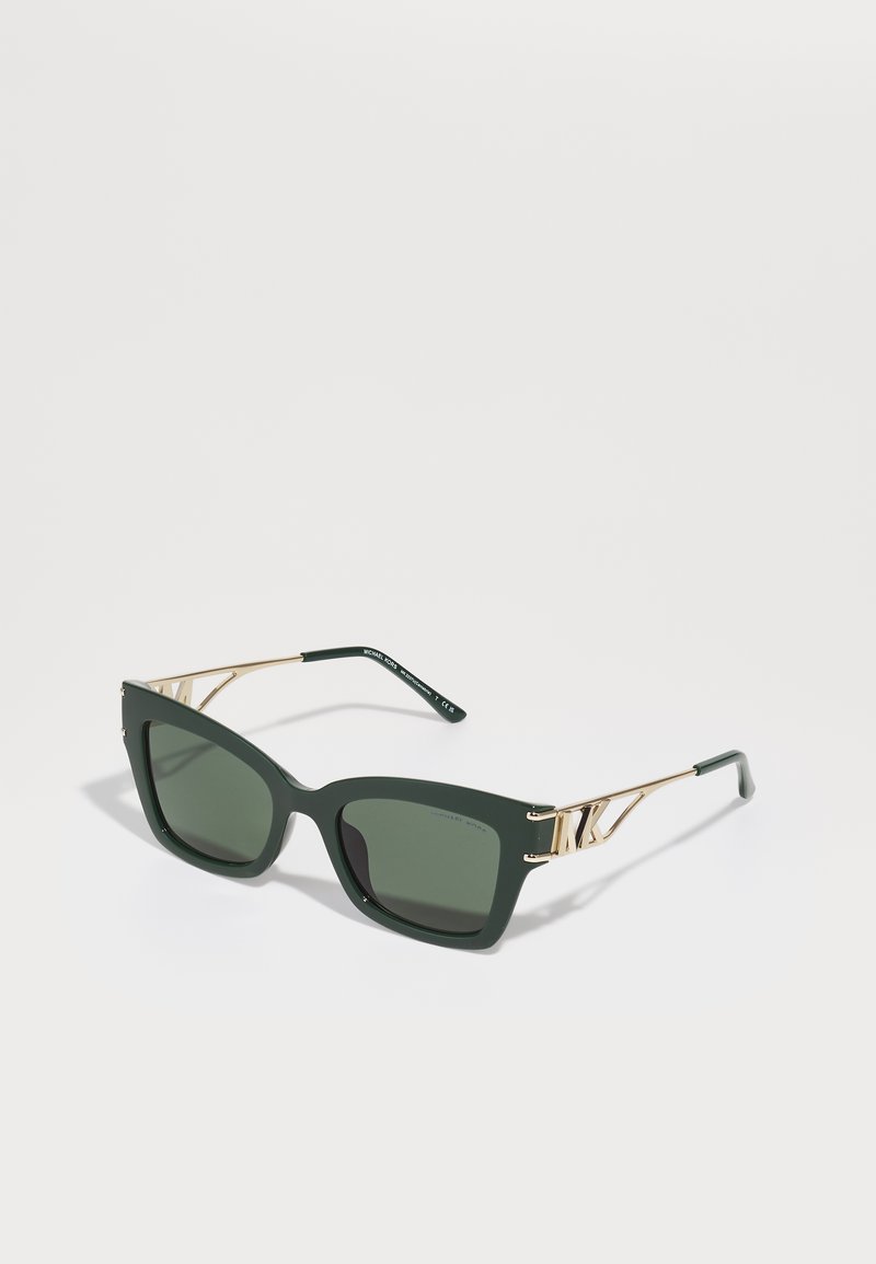 Óculos de sol estilo gato verde com lentes escuras, detalhes em dourado e acabamentos metálicos nas hastes. O acabamento mate na armação adiciona textura.