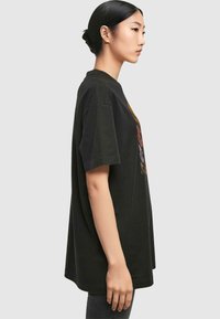 Schwarzes Baumwoll-T-Shirt mit kurzen Ärmeln, ausgestattet mit einem bunten Grafikdesign auf der Vorderseite, lockerer Schnitt und rundem Halsausschnitt.
