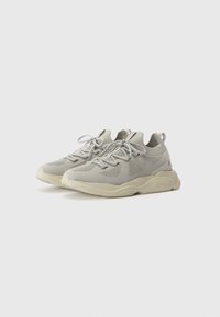 Light gray sneaker featuring a breathable mesh upper, textured accents, flat laces, and a chunky beige sole. Rounded toe and cushioned design.