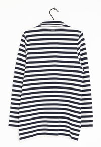 Navy ja valkoisin vaalein vaakaraitoin varustettu pitkähihainen takki, jossa on kaulus, roikkuu mustassa ripustimessa valkoista taustaa vasten.