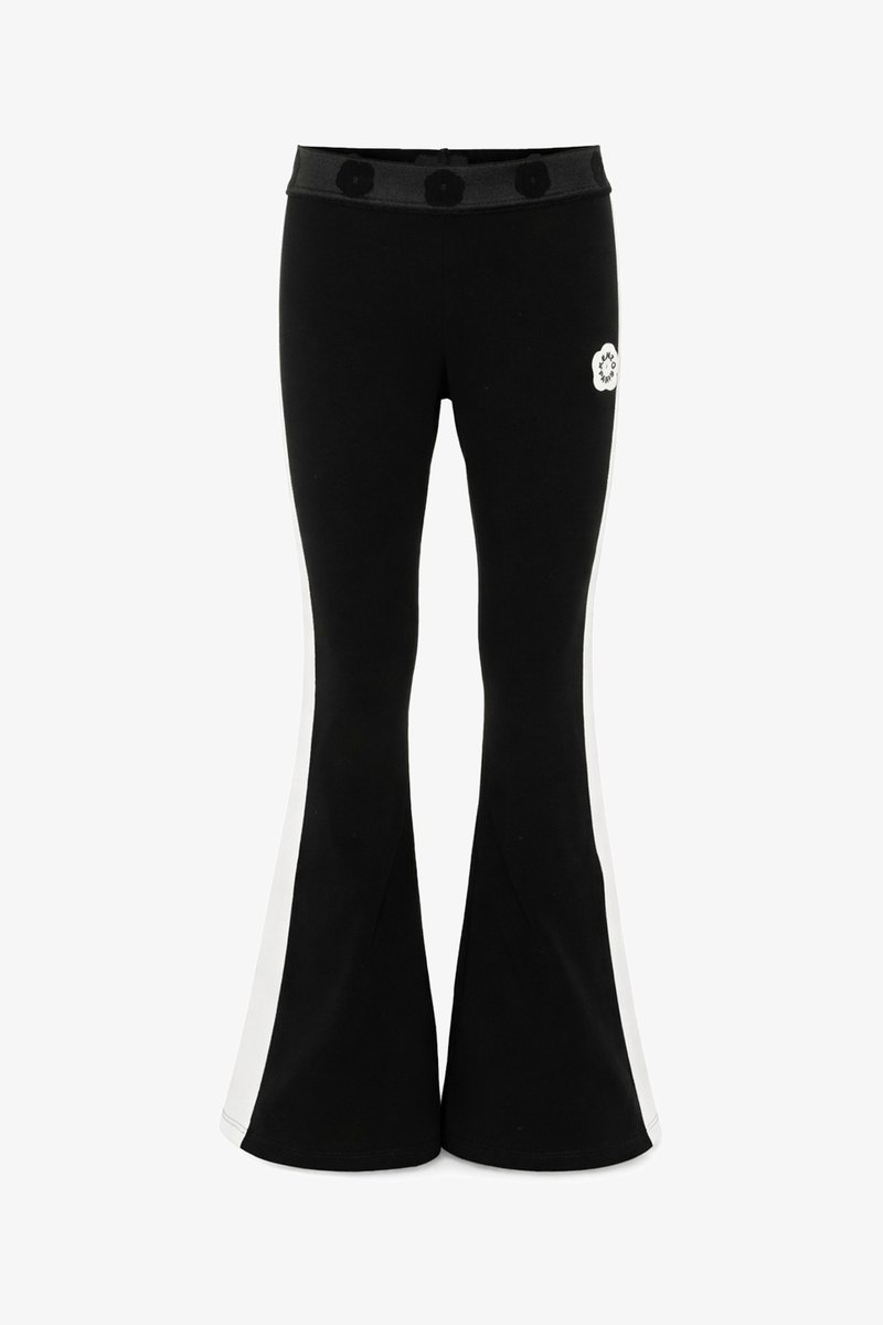 Pantalon noir évasé avec des bandes blanches sur les côtés, une taille élastique avec des détails circulaires et un petit logo circulaire blanc sur le haut de la cuisse.