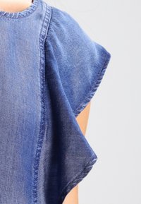 Blue denim top featuring a round neckline and flared short sleeves. The fabric has a light wash and visible stitching accents.