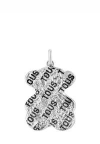Ciondolo a forma di orsetto in argento con superficie strutturata, decorato sul davanti dalla parola "TOUS" impressa ripetutamente in nero.