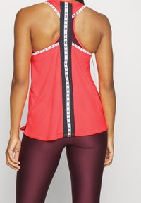 Rode sportieve tanktop met een racerback ontwerp, voorzien van een zwarte verticale streep met "Under Armour" branding in het midden.