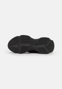 Schwarze Gummisohle mit strukturiertem Profilmuster und konturiertem Design; verfügt über Rillen für Traktion und eine leichte Designunterscheidung in der Mitte.