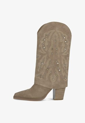 Szary zamszowy but z wydłużonym noskiem, dekoracyjnym przeszyciem i akcentami z ćwiekami; ma gruby obcas z teksturowanym metalowym detalem.