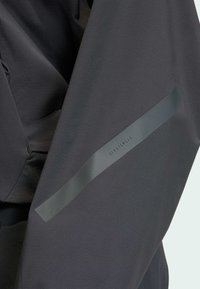 Fekete sportzakó texturált anyagból. Elegáns kialakítás, "SPORTSWEAR" felirattal ellátott szalag és finom varrási részletek jellemzik.