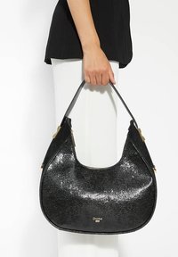 Black glitter handbag with a smooth, curved shape. Features a gold logo and dual-textured black straps. Zipper closure along the top.
