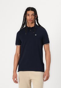 Navy blue polo shirt made of cotton, featuring a classic collar, short sleeves with white accents, and a small logo on the chest.