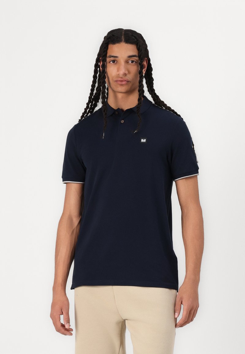 Navy blue polo shirt made of cotton, featuring a classic collar, short sleeves with white accents, and a small logo on the chest.