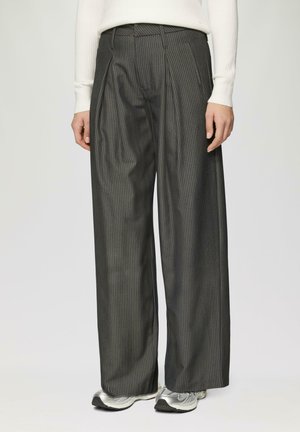 Wijde broek in donkergrijs met een streepjespatroon. Heeft plooien, een klassieke tailleband en is gemaakt van een soepele stof. Geaccentueerd met sneakers.