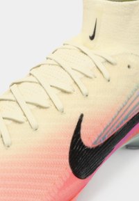 Svijetložute fudbalske kopačke s gradijentnim ružičastim dizajnom, crnim Nike swoosh logotipom, teksturiranim materijalom i šest otvora za vezivanje.
