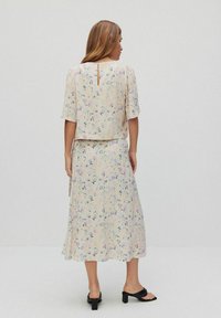 Blommigt tvådelat set i mjukt, lätt tyg. Har en lös topp med korta ärmar och en längre kjol med pastellfärgade blommönster.