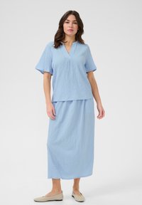 Light blue two-piece outfit featuring a short-sleeved top with a v-neckline and a matching ankle-length skirt, both in textured fabric.