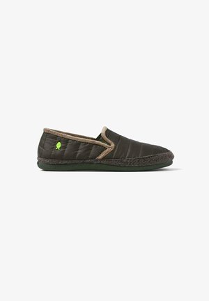 Zapatillas de casa de color verde oscuro, tipo slip-on, con textura acolchada, forro de felpa beige y un pequeño logo verde en el lateral. Suela de goma para un buen agarre.
