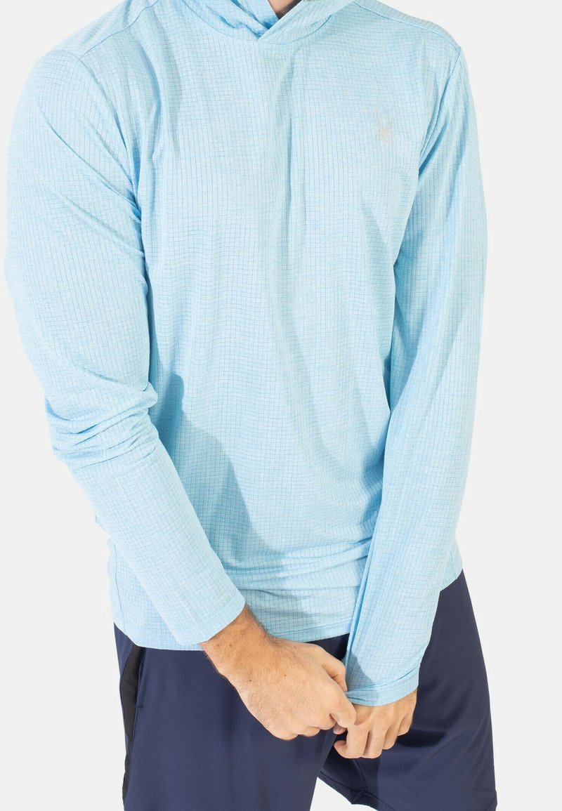 Light blue long-sleeve hoodie with a textured grid pattern, featuring a drawstring hood and fitted cuffs. Worn over navy shorts.