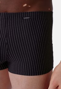 Boxer briefs a righe bianche e nere con una texture morbida. Presentano un elastico con marchio, una vestibilità aderente e una lunghezza fino a metà coscia.