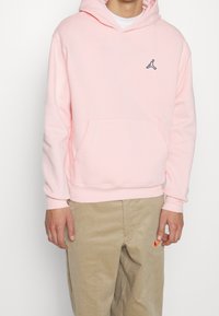 Felpa rosa chiaro in misto cotone, con tasca a marsupio, polsini a coste e un piccolo logo nero sul petto.