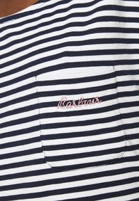 Granatowo-biała koszulka w paski z małą kieszonką na piersi, z różowym haftowanym logiem "Barbour", wykonana z miękkiego, oddychającego materiału.