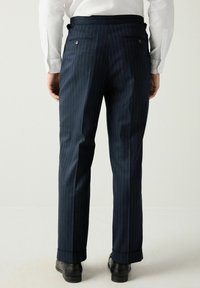 Blue pinstriped trousers made of fabric, featuring a straight cut, two back pockets with buttons, and a cuffed hem. Worn with black shoes.
