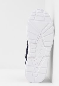 Baskets navy avec une tige texturée, dotées d'une semelle extérieure en caoutchouc blanc. La semelle arbore un motif géométrique pour l'adhérence et la stabilité.