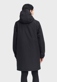 Cappotto nero impermeabile con cappuccio, dotato di maniche lunghe e lunghezza fino a metà coscia. Texture liscia e design minimalista senza hardware visibile.