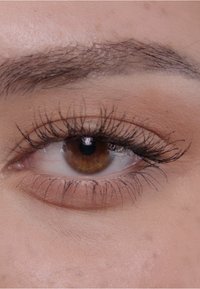 Zbliżenie brązowego oka z długimi, ciemnymi rzęsami, gładką skórą wokół oka i subtelnym cieniem na powiece.