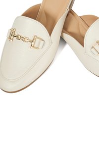 Witte, gestructureerde leren loafers met gouden hardware-accenten. Het ontwerp heeft een ronde neus en een platte zool, wat een klassieke uitstraling biedt.