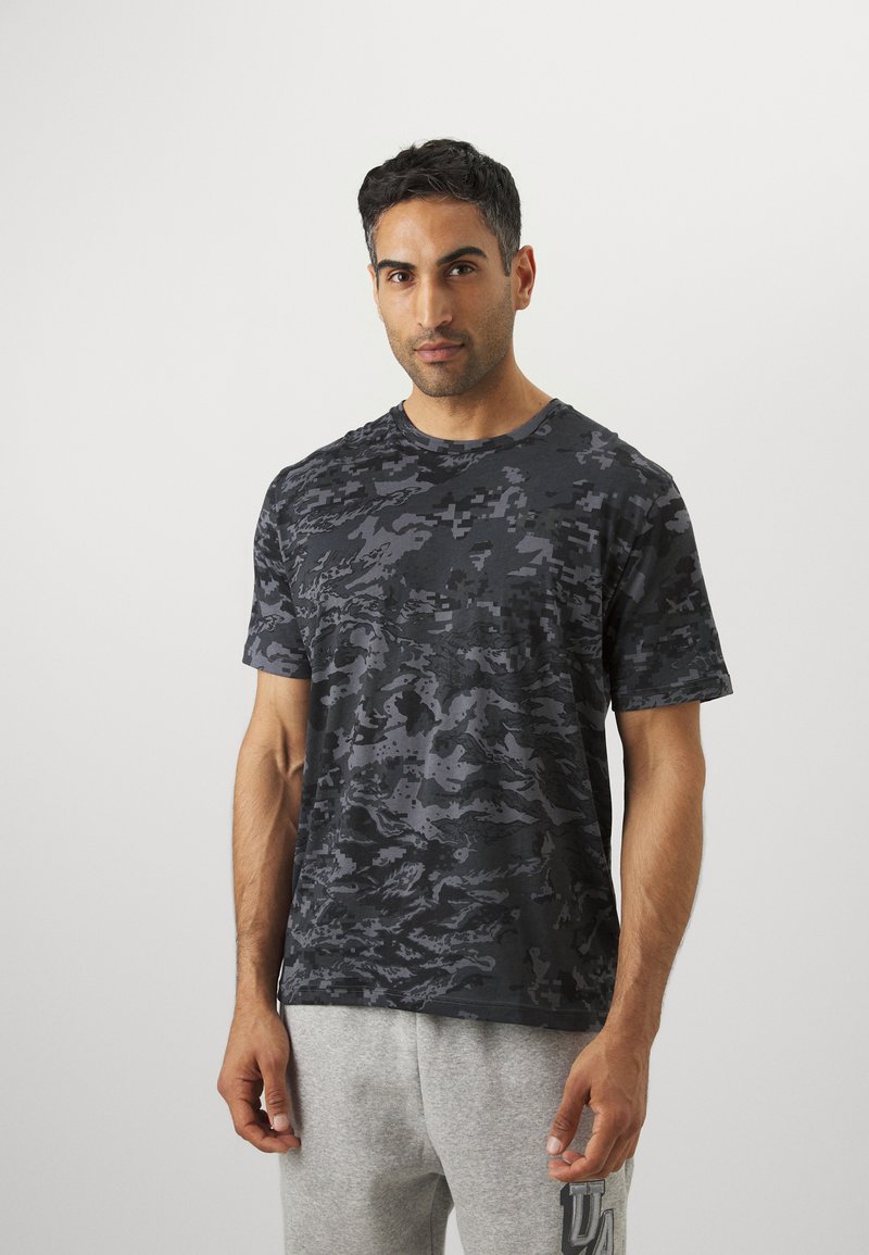 Sort camouflage t-shirt med blødt, let stof, korte ærmer og rund halsudskæring. Bæret med grå sweatpants for kontrast.
