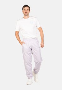 Lichte lila sweatpants met een elastische tailleband, zijzakken en elastische boorden, gecombineerd met een witte t-shirt met ronde hals en een logo.