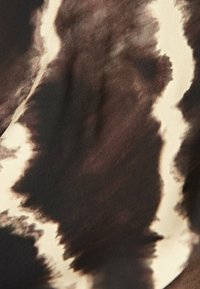 Abstract fabric featuring a brown and cream tie-dye pattern with smooth texture, soft drape, and blended color gradients.