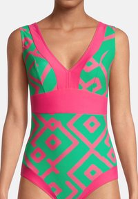 Maillot de bain une pièce avec une base verte ornée de motifs géométriques roses, décolleté en V profond, bande de corsage rose et texture lisse.