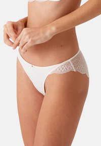 Witte slip met kanten rand, voorzien van een soepel tailleband en verfijnde kantaccenten, die een gegolfde rand en delicate details benadrukken.