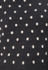 Sweter w ciemnonawowym dzianinowym splocie z równomiernie rozmieszczonymi kremowymi kropkami. Miękka tekstura z widocznymi włóknami, nadająca przytulny wygląd.