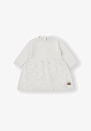 Vestido blanco de bebé de manga larga con falda acolchada texturizada y puños, cuello y dobladillo acanalados, con un pequeño parche marrón en la falda.