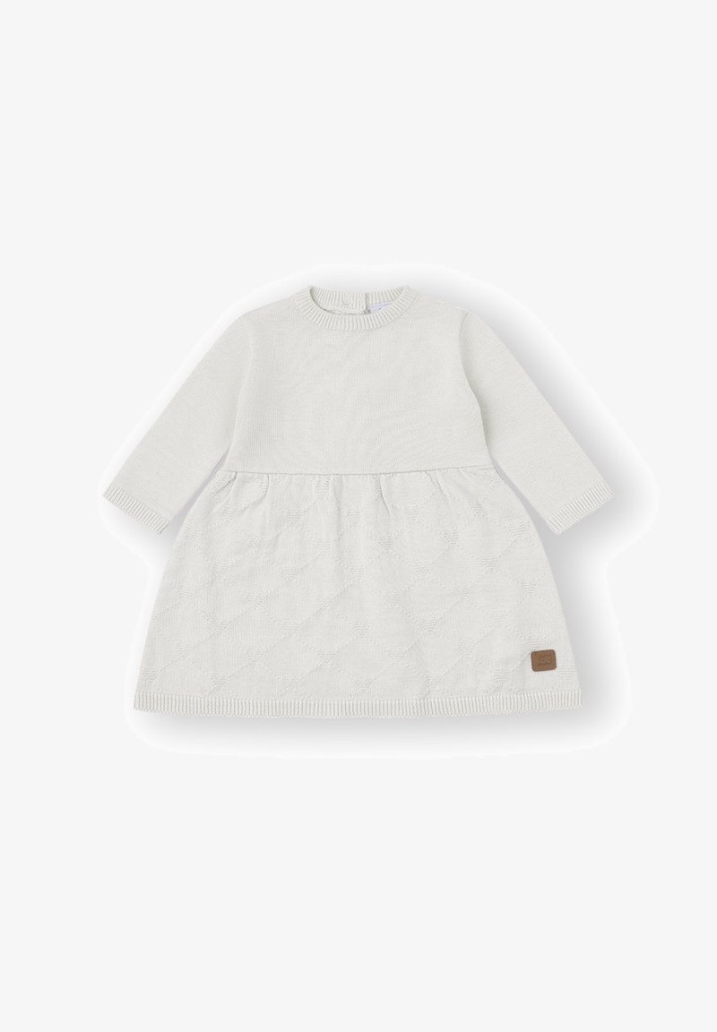 Vestido blanco de bebé de manga larga con falda acolchada texturizada y puños, cuello y dobladillo acanalados, con un pequeño parche marrón en la falda.